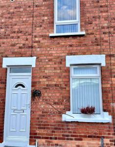 a brick building with two windows and a white door at Stay-K-Belfast Cosy house 10 mins from city centre in Belfast