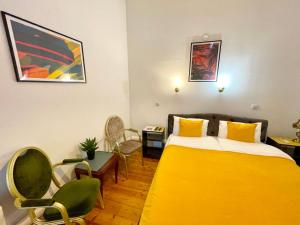 pokój hotelowy z żółtym łóżkiem i krzesłami w obiekcie The Only One Suites w Niszu