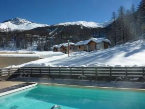 a swimming pool in the snow next to a building at Chalet mitoyen aux Orres avec piscine chauffée, sauna, hammam - skis aux pieds - 6 pers. - FR-1-322-110 in Les Orres
