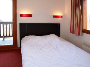 a bed in a bedroom with two lights on the wall at Chalet Les Orres, 3 pièces, 6 personnes - FR-1-322-124 in Les Orres