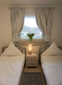 2 Betten in einem Zimmer mit Fenster und Lampe in der Unterkunft Großzügige Ferienwohnung im OT Bad, Strandnähe in Sankt Peter-Ording