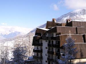 a building in the snow with mountains in the background at Appartement Les Orres, 1 pièce, 4 personnes - FR-1-322-175 in Les Orres