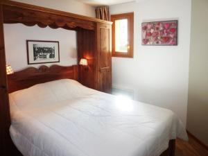 a bedroom with a white bed with a wooden headboard at Appartement Les Orres, 2 pièces, 8 personnes - FR-1-322-202 in Les Orres