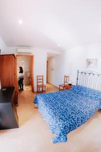 una mujer parada en un dormitorio con una cama azul en Hotel Delphos, en Moraleja