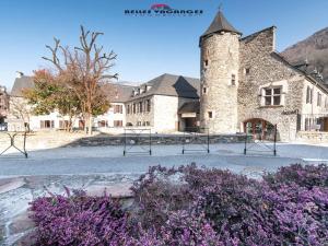 - un grand bâtiment en pierre avec une tour ornée de fleurs violettes dans l'établissement Appartement Saint-Lary-Soulan, 3 pièces, 6 personnes - FR-1-296-143, à Saint-Lary-Soulan