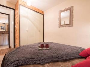 a bedroom with a bed with a mirror and two cups at Appartement Saint-Lary-Soulan, 2 pièces, 4 personnes - FR-1-296-174 in Saint-Lary-Soulan