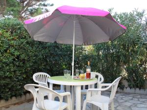 einen Tisch und Stühle mit einem rosa Regenschirm in der Unterkunft Maison Port-la-Nouvelle, 4 pièces, 8 personnes - FR-1-229C-28 in Port-la-Nouvelle