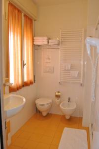 ein weißes Bad mit einem WC und einem Waschbecken in der Unterkunft Hotel La Baia in Diano Marina