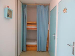 een slaapkamer met een stapelbed en een kast met blauwe gordijnen bij Appartement Vieux-Boucau-les-Bains, 2 pièces, 5 personnes - FR-1-379-24 in Vieux-Boucau-les-Bains