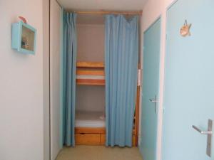 ein Schlafzimmer mit einem Etagenbett und einem Schrank mit blauen Vorhängen in der Unterkunft Appartement T2 Cabine à Vieux-Boucau avec Balcon, Animaux Admis - FR-1-379-24 in Vieux-Boucau-les-Bains