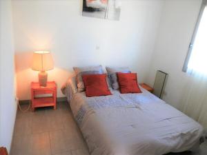 a bedroom with a bed with red pillows and a lamp at Appartement Vieux-Boucau-les-Bains, 2 pièces, 4 personnes - FR-1-379-27 in Vieux-Boucau-les-Bains