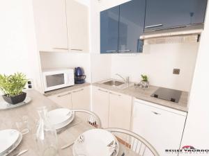 a kitchen with white cabinets and a table with chairs at Appartement 4 personnes à Saint Lary village - FR-1-296-231 in Saint-Lary-Soulan