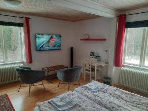Zimmer mit 2 Stühlen und einem TV an der Wand in der Unterkunft Geijersholms Herrgård in Hagfors