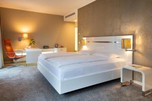a bedroom with a large white bed and a chair at INNSiDE by Meliá Dresden in Dresden