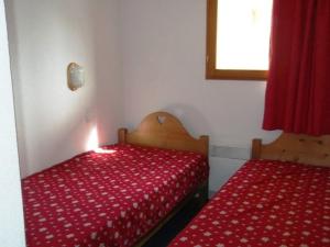 a bedroom with two beds with red sheets and a window at Appartement Orcières Merlette, 3 pièces, 6 personnes - FR-1-262-154 in Les Estaris