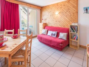 ein Wohnzimmer mit einem roten Sofa und einem Tisch in der Unterkunft Appartement cosy avec balcon, parking privé et à 400m des télécabines – Centre-ville Briançon - FR-1-330C-19 in Briançon