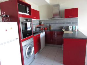 eine Küche mit roten Schränken und einer Waschmaschine in der Unterkunft Appartement Étel, 2 pièces, 4 personnes - FR-1-479-76 in Étel