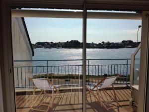 - deux chaises sur un balcon avec vue sur l'eau dans l'établissement Appartement Étel, 2 pièces, 4 personnes - FR-1-479-76, à Étel