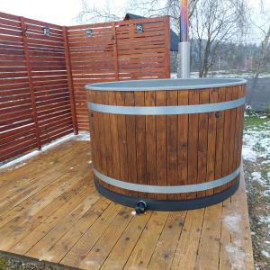 a wooden barrel on a deck with a fence at Na wilczym szlaku in Ustrzyki Dolne