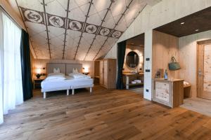 a bedroom with a bed and a coffered ceiling at Dolomites Living Hotel Tirler in Alpe di Siusi