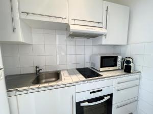 - une cuisine blanche avec évier et four micro-ondes dans l'établissement Appartement Cannes, 2 pièces, 4 personnes - FR-1-470-11, à Cannes