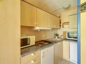 a small kitchen with white cabinets and a microwave at Studio La Mongie, 2 pièces, 8 personnes - FR-1-404-110 in La Mongie
