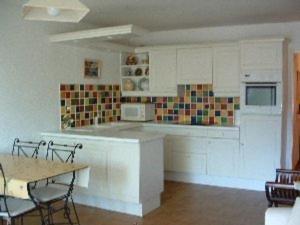 a kitchen with white cabinets and a table with chairs at Appartement Argelès-sur-Mer, 2 pièces, 4 personnes - FR-1-388-31 in Argelès-sur-Mer