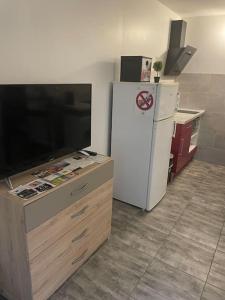 cocina con nevera blanca y TV en Superbe appartement terrasse wifi, en Paroy-sur-Tholon