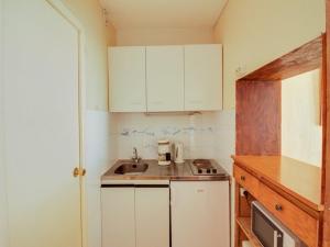 une petite cuisine avec des armoires blanches et un évier dans l'établissement Studio 4 pers avec balcon, centre-ville, proche télécabine, idéal famille – Cauterets - FR-1-401-53, à Cauterets 10 autres photos