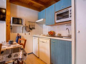 a kitchen with blue cabinets and a table and a microwave at Appartement cosy 4 pers avec parking, terrasse, local à skis - FR-1-403-21 in Barèges +4 photos