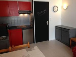 ラ・モンジーにあるStudio La Mongie, 2 pièces, 6 personnes - FR-1-404-111の赤いキャビネットと壁掛け時計付きのキッチン