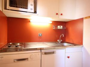 uma cozinha com paredes cor de laranja, um fogão e um lavatório. em Studio Peisey-Vallandry, 1 pièce, 4 personnes - FR-1-411-75 em Landry