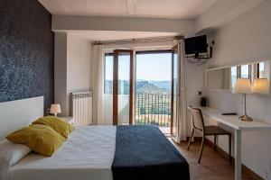 sypialnia z łóżkiem, biurkiem i oknem w obiekcie Hotel El Cid w mieście Morella