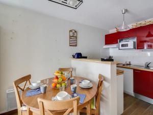 une cuisine avec une table et des chaises et une cuisine avec des placards rouges dans l'établissement Appartement 6 personnes avec parking et wifi à Barèges - FR-1-403-78, à Barèges