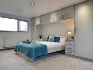 una camera da letto con un grande letto bianco con cuscini blu di Spacious City Home with Free Parking, Fast Wi-Fi & Netflix a Coventry