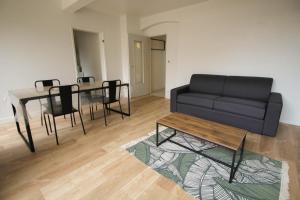 ein Wohnzimmer mit einem schwarzen Sofa und einem Tisch in der Unterkunft Le patio de Théo - proche gare - centre-ville in Angoulême