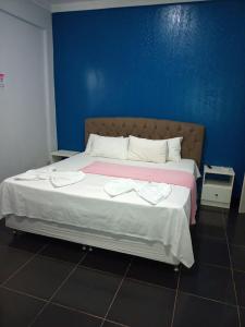 a bedroom with a large bed with a blue wall at Topazzo Hotel in Uruara