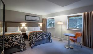 a hotel room with two beds and a chair at Clayton Hotel Bristol City in Bristol