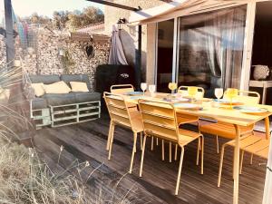 Une table à manger en bois et des chaises sont disponibles sur la terrasse. dans l'établissement L'Escapade, Magnifique Villa avec Piscine, à Collias