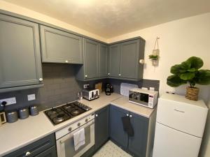 eine Küche mit blauen Schränken und einem weißen Kühlschrank in der Unterkunft Coney Green Way - close to PRH in Wellington