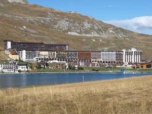 un grande edificio vicino a un lago di fronte a una montagna di Studio cosy à Tignes, au pied des pistes et commerces - FR-1-411-481 a Tignes