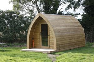 um pequeno barracão de madeira com uma porta na relva em Wolds Glamping em Pocklington