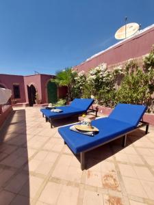 une rangée de tables de pique-nique bleues sur une terrasse dans l'établissement Riad Kenzo, à Marrakech