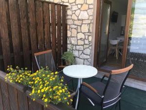 a patio with a table and chairs and flowers at Guesthouse Family Bosnic in Plitvička Jezera