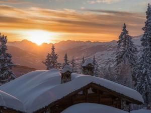 una cabaña cubierta de nieve con la puesta de sol en el fondo en Studio Montvalezan-La Rosière, 1 pièce, 4 personnes - FR-1-398-573, en Montvalezan