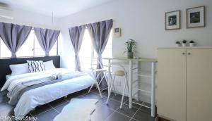 a bedroom with a bed and a desk and windows at NEW Heart of Shibuya Prime Studio, Kamiyama Inn! in Tokyo