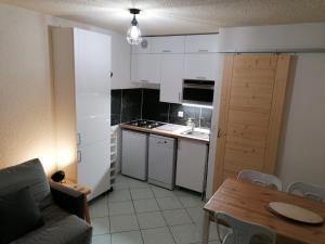 a kitchen with white cabinets and a table and a couch at Studio La Clusaz, 1 pièce, 4 personnes - FR-1-459-64 in La Clusaz