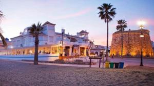 a large white building with palm trees in front of it at Beach apartment LA CALA DE MIJAS in La Cala de Mijas