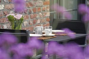 une table avec des assiettes et des verres avec des fleurs violettes dans l'établissement A Coque'Line, à Frasnes-lez-Anvaing