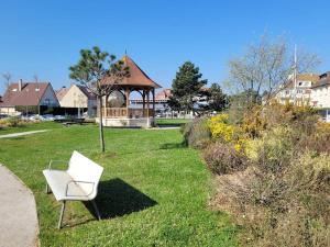 una silla blanca sentada en un patio con cenador en Appartement Merville-Franceville-Plage, 2 pièces, 4 personnes - FR-1-465-26, en Merville-Franceville-Plage